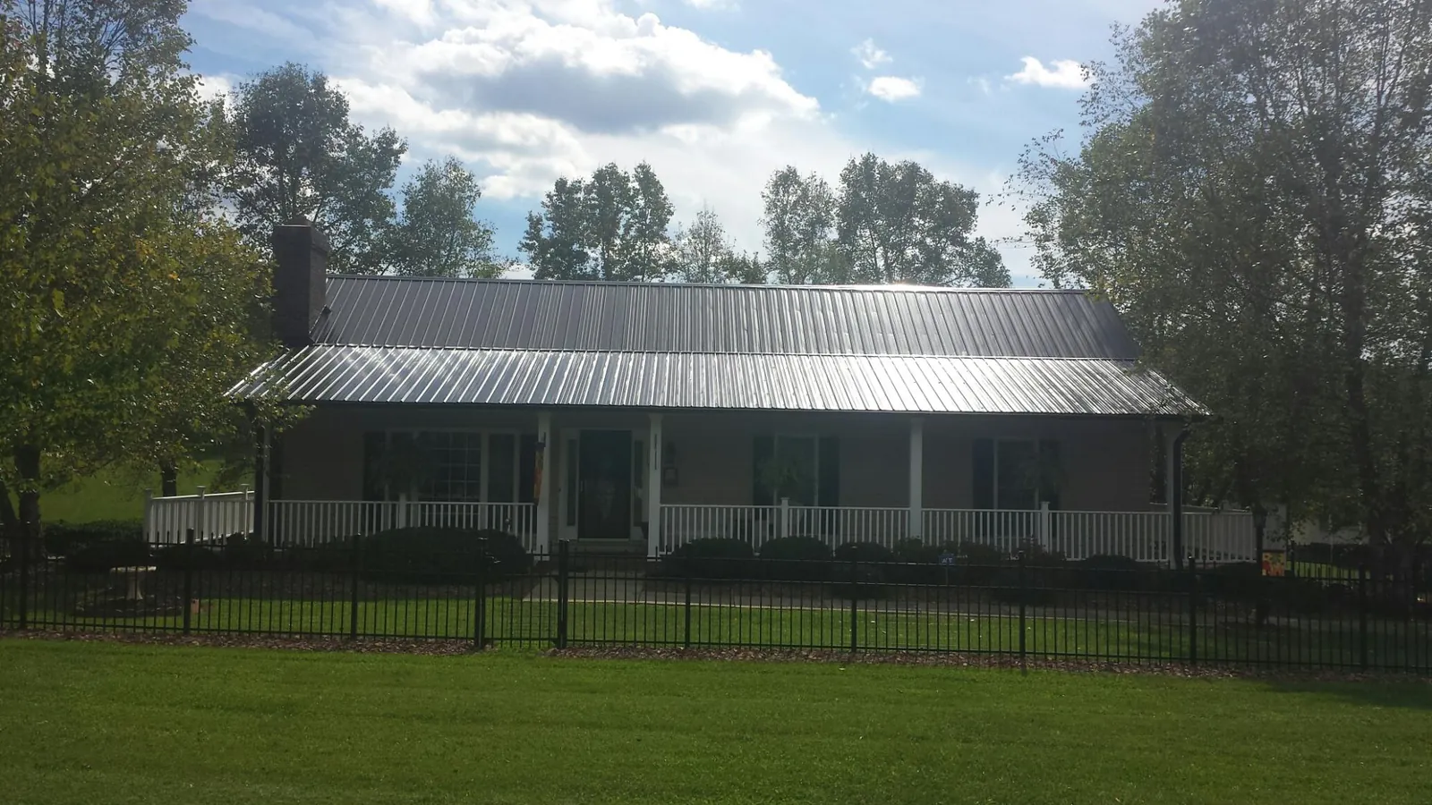 Gray metal roof on a brick ranch with a full width front porch — Gutter Guard Installation work by our crew in Sanborn