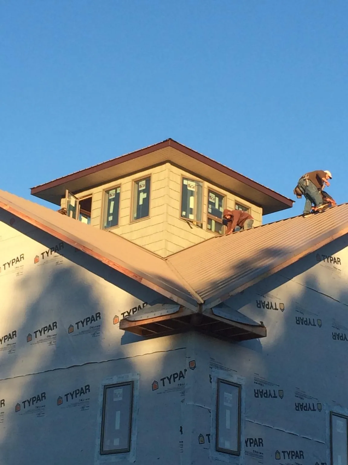 Roofers working around a rooftop cupola on a new metal roof at sunset — Roof Waterproofing in Sanborn by Roofing Brothers